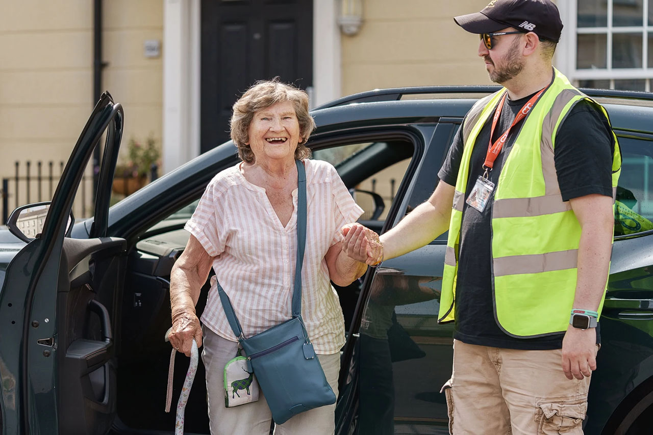 Travel Safely with Community Connexion staff supporting elderly person to leave community transport